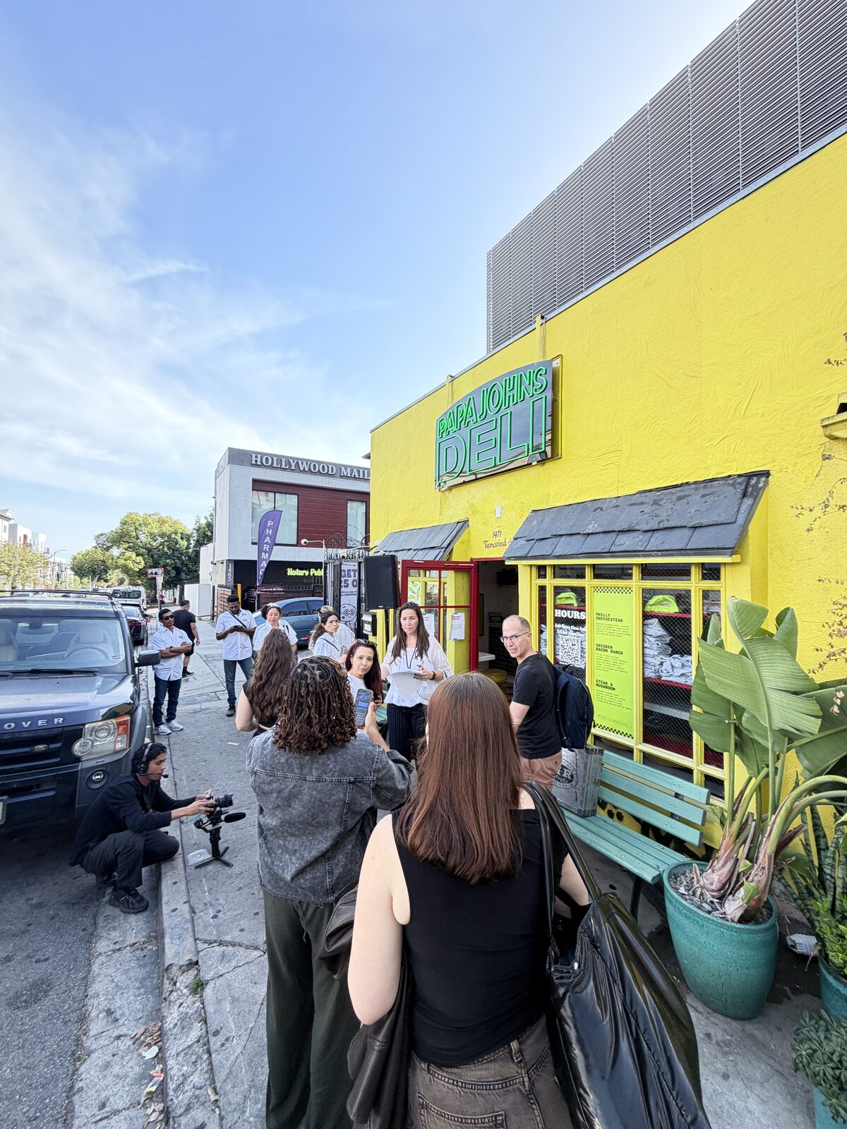 Outdoor popup storefront with caps and blanks visible in the window during a Hollywood street fair